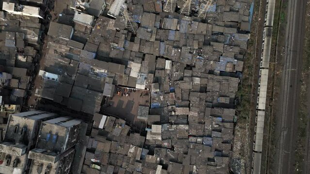 Top down aerial view of train passing next to Dharavi slums in Mumbai, Maharashtra, India. Dharavi is considered to be one of the largest slums in the world and the largest in Asia. 