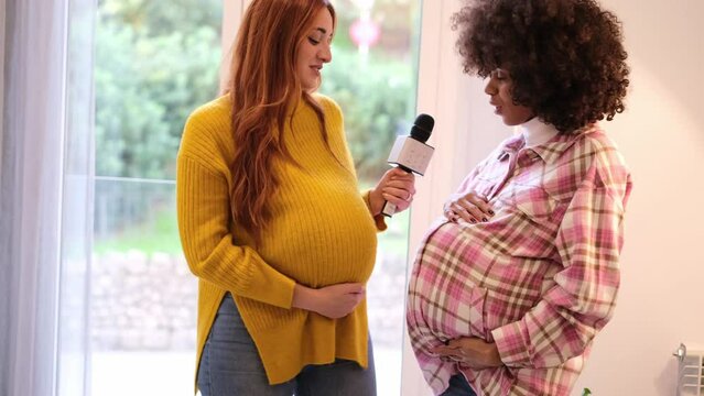 Two young pregnant women exercising and singing to entertain themselves and better carry the pregnancy. Concept: motherhood, fun, pride
