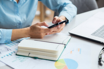 Fototapeta premium Business background. Business woman holding a mobile phone in her hands, working, sitting at the office desktop