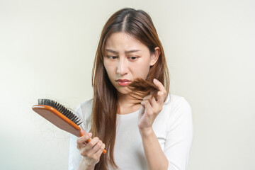 Serious, worried asian young woman, girl holding brush, show her comb, hairbrush with long loss...