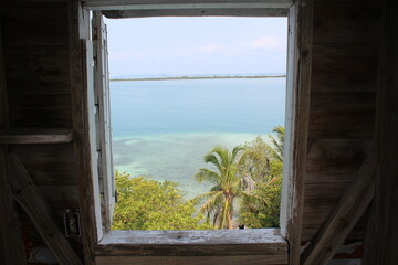 a distant tropical island seen through a wooden window frame