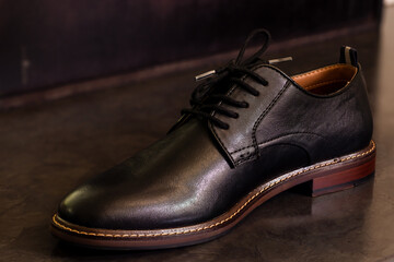 Fototapeta na wymiar Side view of black formal leather shoe on a black floor. Mens formal shoes