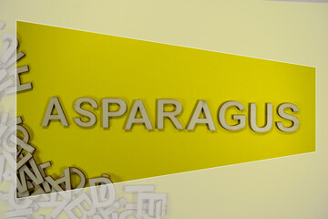 ASPARAGUS in wooden English words language capital letters spilling from a pile of letters on a yellow background framed