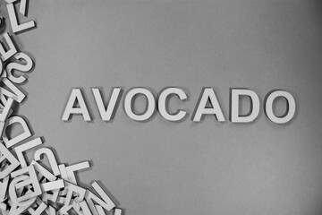AVOCADO in wooden English language capital letters spilling from a pile of letters in black and white