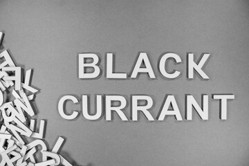 BLACK CURRANT fruit in wooden English language capital letters spilling from a pile of letters in black and white