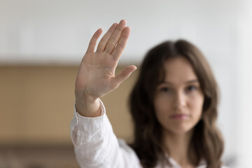 Serious young woman showing palm at camera, posing with hand stop gesture, standing against force, abuse, saying no domestic violence. Female model girl protest portrait with arm close up