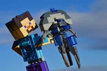 Fototapeta premium LEGO Minecraft figure of Steve examining model of space ship Jellyfish from Star Trek movie series (known as ship of Mr. Spock from planet Vulcan) in vertical position. Blue sky.