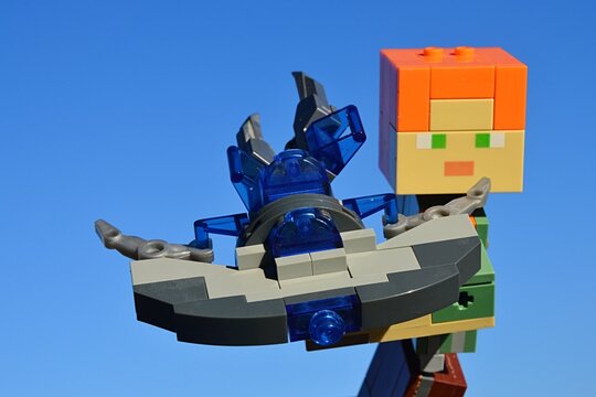 LEGO Minecraft large figure of Alex holding model of Start Trek Vulkan spaceship Jellyfish (piloted by famous Mr. Spock in movie ant TV series), looking forward. Blue winter skies in background.