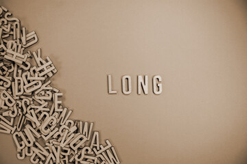 LONG in wooden English language capital letters spilling from a pile of letters in sepia