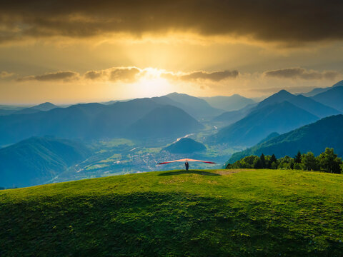 Hang glider ready to launch from the green meadow in the mountains