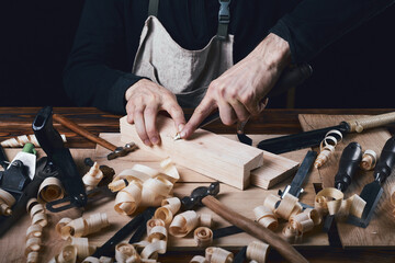 Carpenter's hands working with wood using a chisel. Handmade concept. Carpenter's table