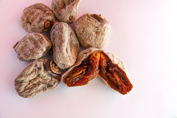 dried persimmons on a white background. one persimmons split in half.