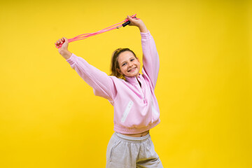 Adorable female child with skipping rope jumping in studio - obrazy, fototapety, plakaty