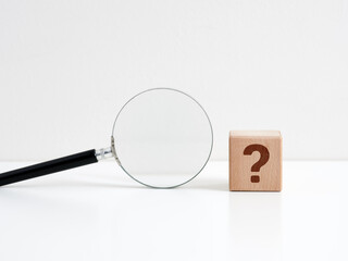 Problem, uncertainty and confusion. Searching for an answer. Problem analysis and solution. Wooden cube with question mark symbol and a magnifying glass.