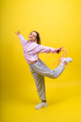 Fototapeta na wymiar Adorable female child with skipping rope jumping in studio