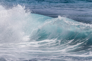Fototapeta premium close-up of a wave breaking against the shoreline and creating lots of white foam. Tenerife, Canary Islands, Spain