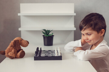 cute boy is playing chess with his toy