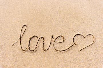 Love word and heart sign handwritten on the sandy beach surface with space for text