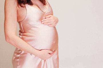 A young pregnant girl in a beautiful pink dress. Pregnancy in the spring. Waiting for the girl