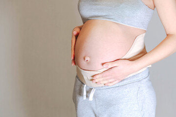 Pregnant woman belly in prenatal pregnancy maternity belt. Orthopedic abdominal support waist, back, abdomen band. Belly brace or band for pregnancy