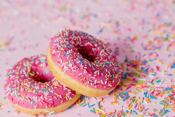 Delicious dessert. Pink donuts with multicolored sprinkles on a pink background of Sweets. Confectionery products.