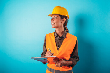 Confident woman architect with an orange helmet does a sketch