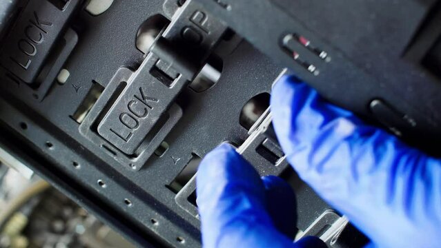 The master closes the lock. A hand in a blue glove closes the locks of the Lock-Open system. The service process of sealing the administrative cabinet of a computer system in a server room. Close-up