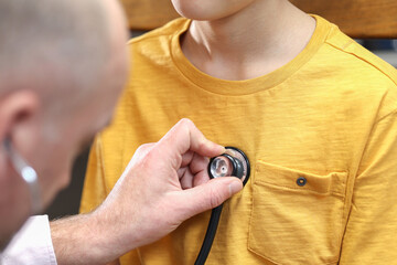 Fototapeta premium Closeup hand of Caucasian male pediatrician use stethoscope do pediatric checkup examination on child boy patient to check heart lungs, children medical care concept. 