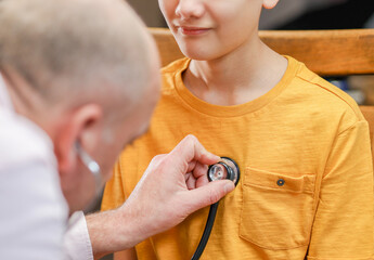 Closeup hand of Caucasian male pediatrician use stethoscope do pediatric checkup examination on child boy patient to check heart lungs, children medical care concept. 