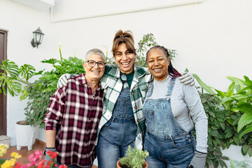 Happy multiracial women gardening together at home