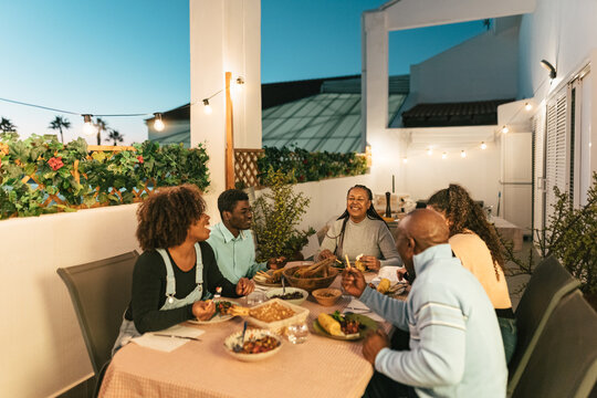 Happy African family dining together on house patio