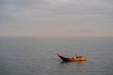 Fisherman sailing the wooden boat in the middle of the ocean during sunrise