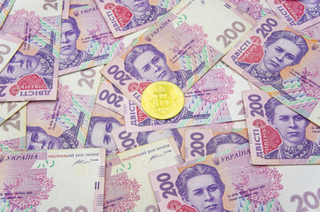 Golden bitcoin on two hundred ukrainian hryvnia bills background