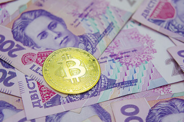 Golden bitcoin on two hundred ukrainian hryvnia bills background