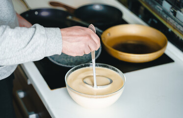 Russia Moscow 14.03.2021 Cooking many big tasty pancakes Lot of pans,oil,pancake dough.Russian traditional national festival winter Maslenitsa holiday week,shrovetide. Man, father cook.Family holiday