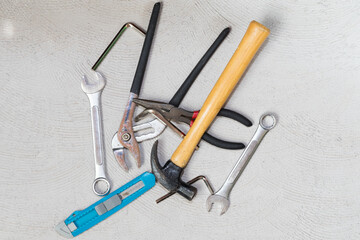 top view tool kit of different kinds hammer, wrenches, pliers on concrete background