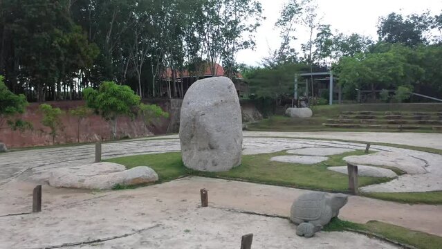 shows the camera moving to the left, rotating around a boulder, an ancient site on Bumi Ragem Sai Mangi Wawai, Lampung Indonesia.
