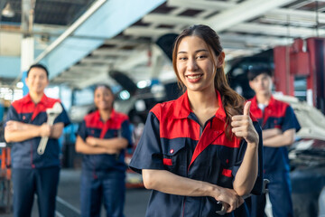 Obraz premium Asian automotive engineer people wear helmet work in mechanics garage.young auto mechanic in uniform is looking at camera and smiling examining car.