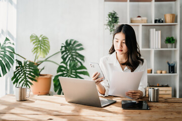  Beautiful Asian business woman typing laptop and tablet Placed at the table at home office.