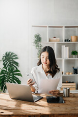  Beautiful Asian business woman typing laptop and tablet Placed at the table at home office.