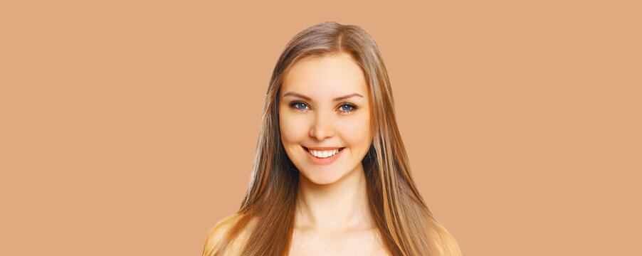 Portrait of beautiful blonde smiling young woman with long hair and cute smile on background