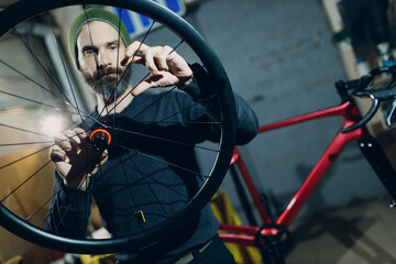 Mechanic repairman assembling check wheel spoke custom bicycle in workshop
