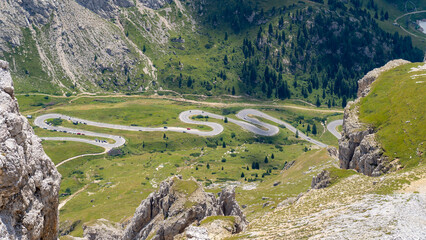 Fototapeta na wymiar Road to the Pordoi mountain pass in Italy. Amazing aerial view of the mountain bends creating beautiful shapes. A famous route of the Italian Alps. Dolomites Unesco world heritage