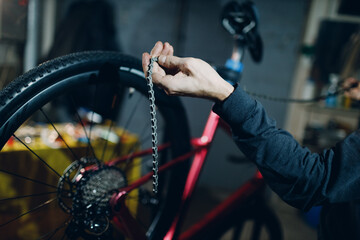 Mechanic repairman assembling custom bicycle installing chain in workshop