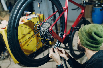 Mechanic repairman assembling custom bicycle installing chain in workshop
