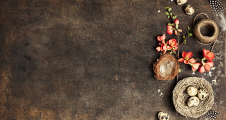 Easter composition, branch with peach blooming flowers and easter decorations on aged table
