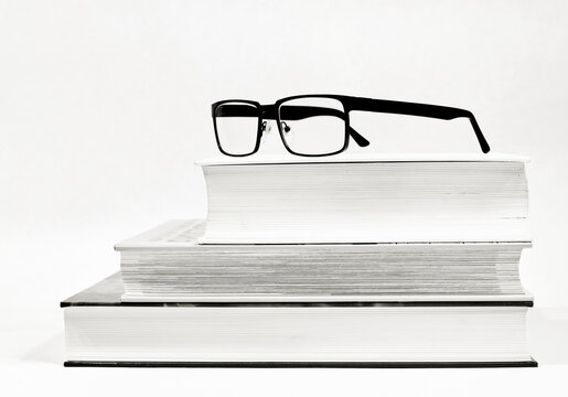 Drei dicke B&uuml;cher und eine Brille als Sehhilfe als Schwarzwei&szlig;bild
