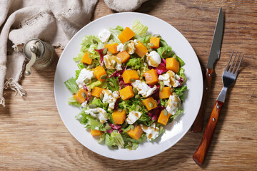 plate of salad with baked pumpkin and cream cheese, top view