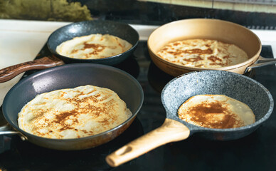 Russia Moscow 14.03.2021 Cooking many big tasty pancakes Lot of pans,oil,pancake dough.Russian traditional national festival winter Maslenitsa holiday week,shrovetide. Man, father cook.Family holiday