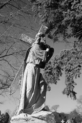 A statue of an older Jesus Christ dragging his cross in black and white.